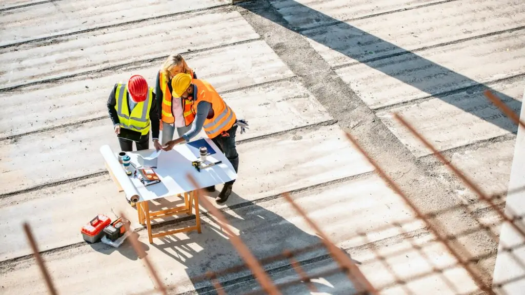 Plusieurs personnes parcourent un permis de construire sur un chantier