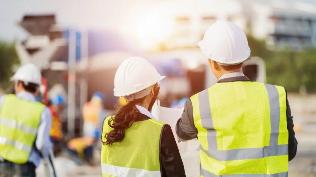 Trois hommes de dos sur un chantier en construction en vefa ou cpi